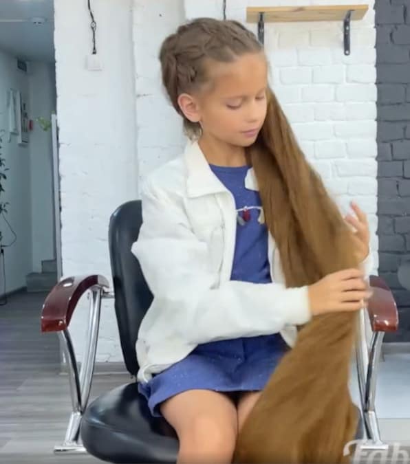 bambina taglia i sui lunghi capelli per aiutare un cane